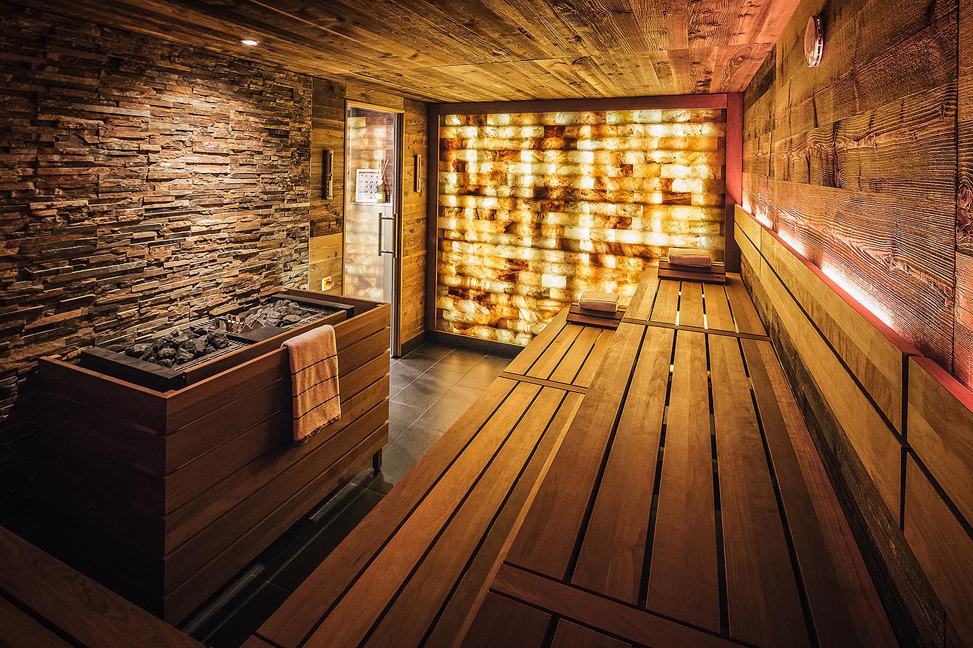 Sauna d’hôtels avec des pierres naturelles et un mur de pierre de sel rétro-éclairé à l’hôtel Quatre Saisons à Hambourg. made by corso.