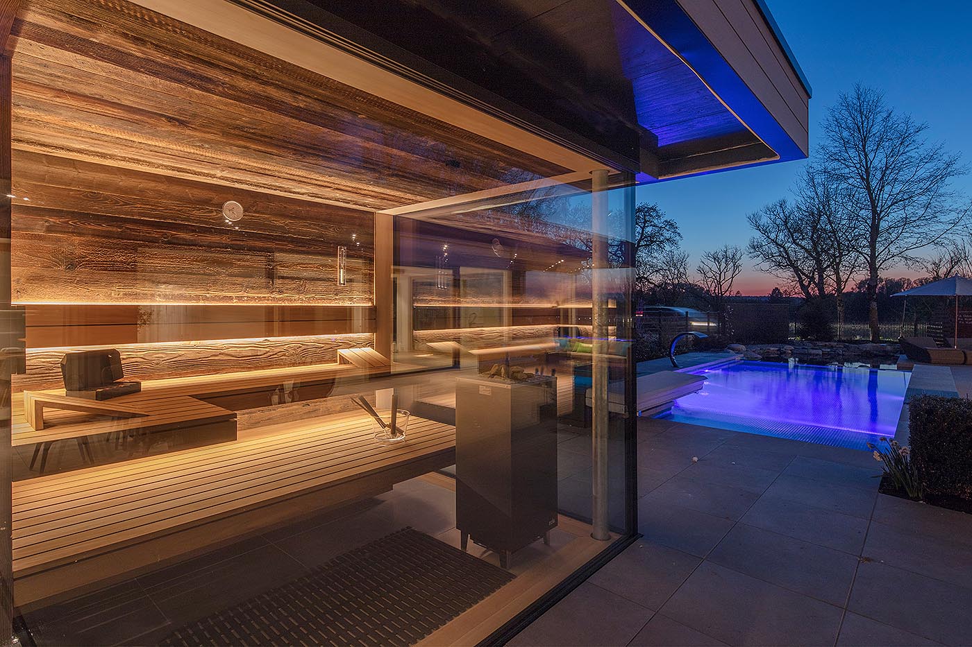 Außensauna in der Sauna Ausstellung in Taufkirchen bei München. Moderne Gartensauna mit Glasfront in Thermo-Espe und Altholz mit frei stehendem Saunaofen.