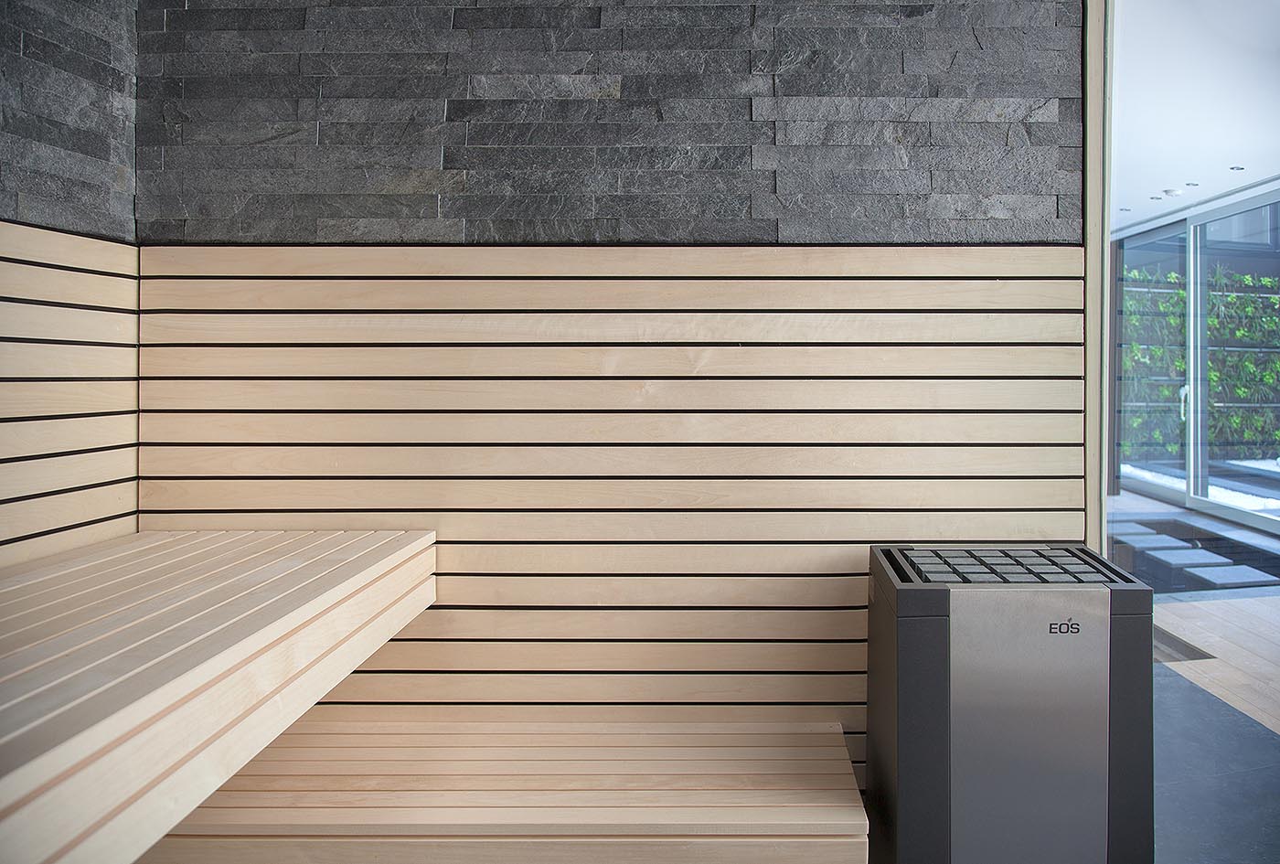 Moderne Design Sauna für Zuhause in heller Espe, Steinwand und Design Saunaofen.
