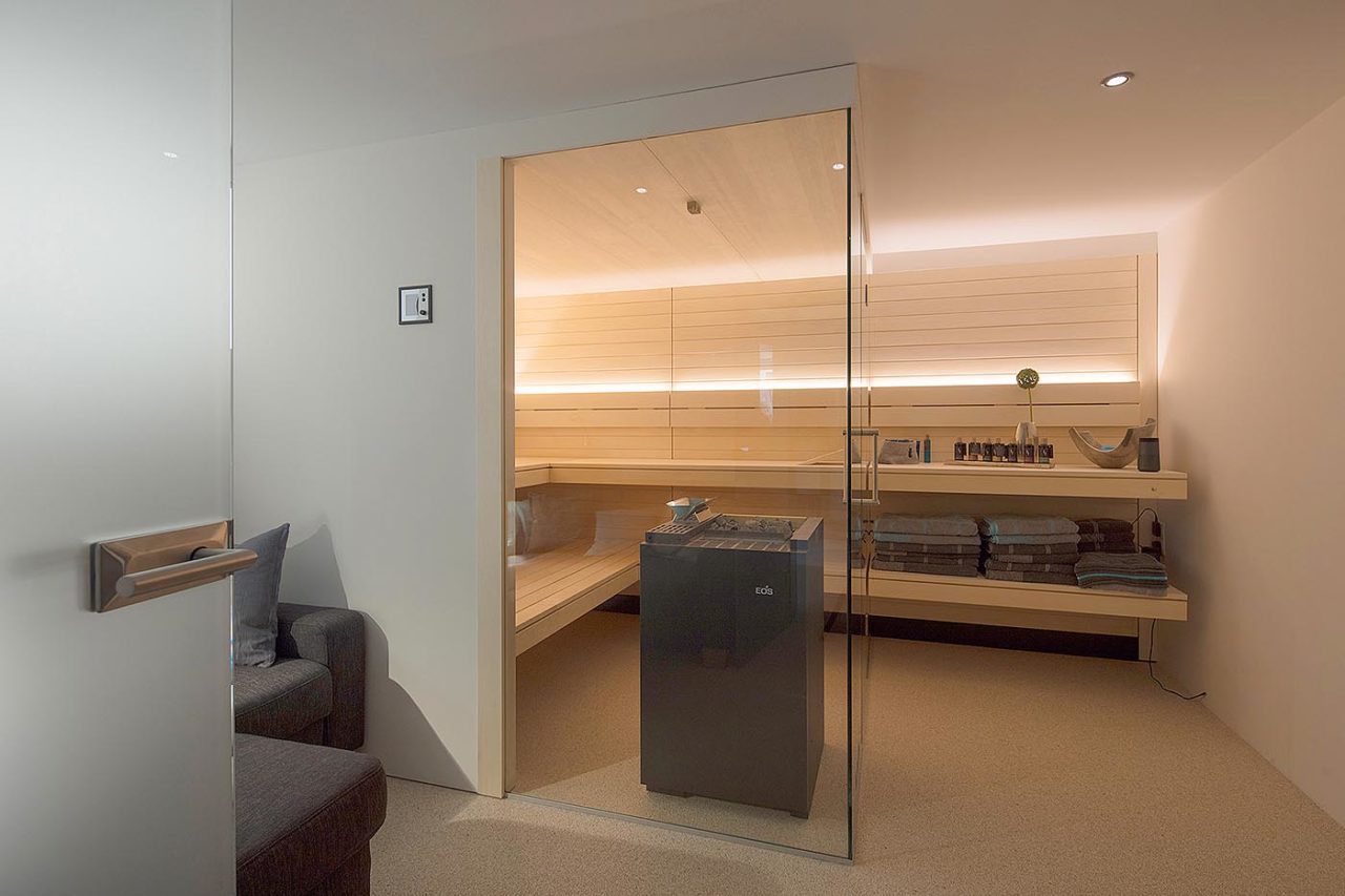 Moderne Heimsauna im Souterrain mit Glasfront bzw. Glasecke und schwebenden, nach außen verlängerten Bänken. Lösung als Ecksauna.