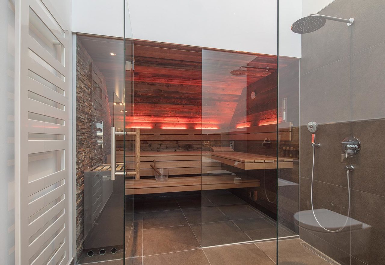 Saunabau Münster: Altholz Sauna mit Glasfront unter Dachschräge, voll integrierte Einbausauna im Bad, direkt neben der Dusche
