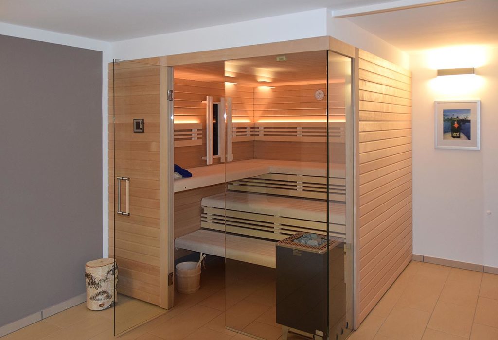 Sauna für Zuhause als Ecksauna mit Glasecke und integriertem Infrarotstrahler in Hemlock. Moderne Heimsauna.