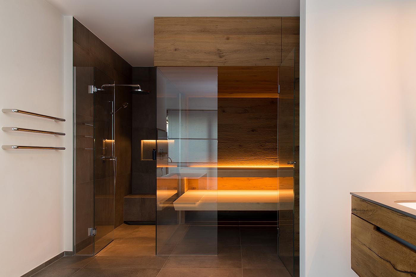 Moderne Ecksauna für Zuhause im Bad mit Glasecke und direkt anschließender Dusche.