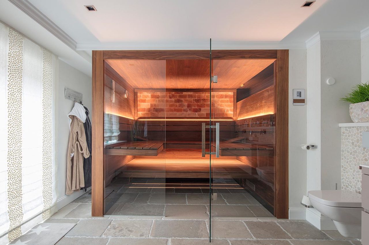 Saunabau: Design Sauna Zuhause im Bad: Premium Sauna aus Nussbaum mit Hinterwandofen, Glasfront, indirekter LED Beleuchtung und schwebenden Bänken.  Luxus Sauna nach Maß von corso sauna manufaktur