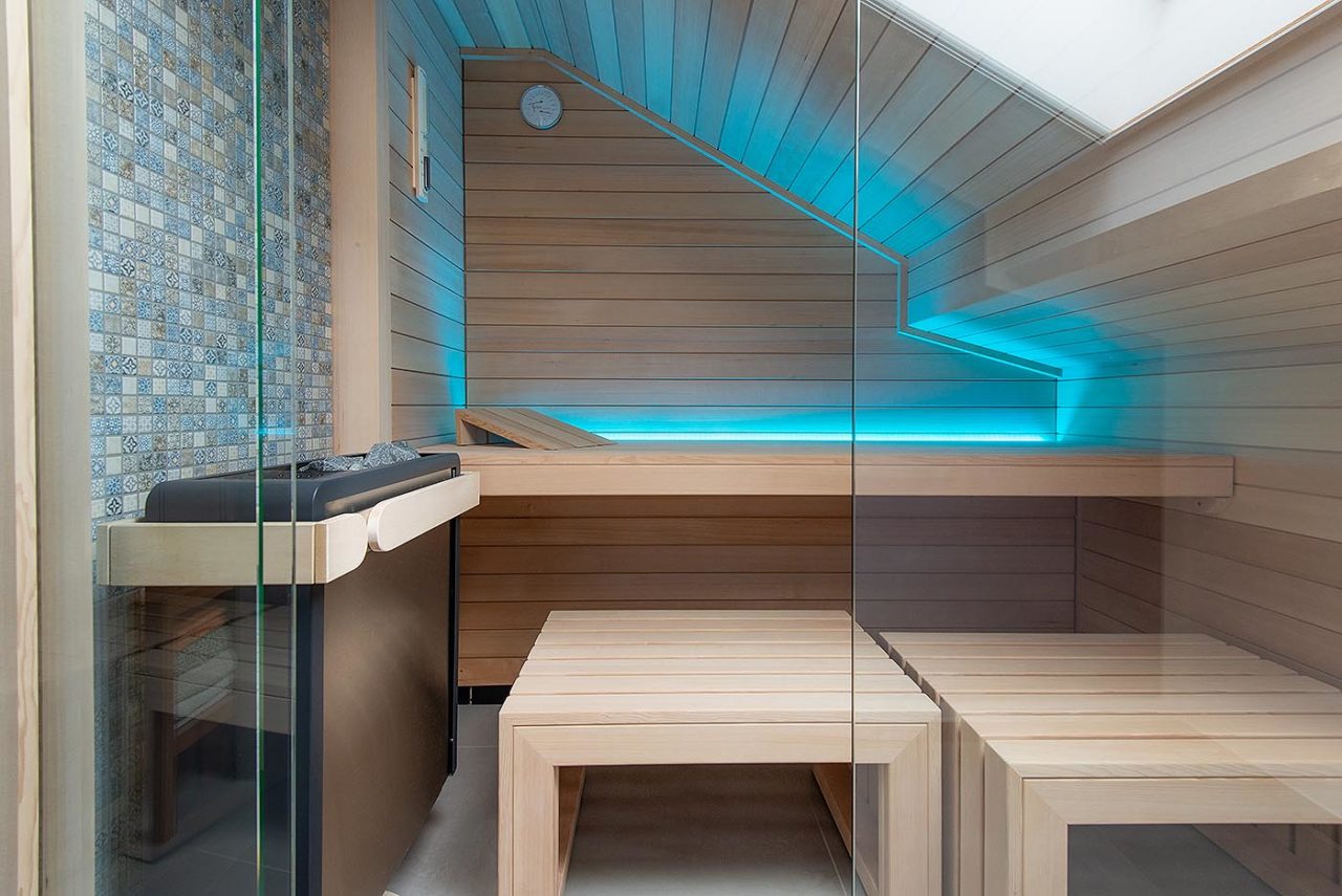 Sauna unter Dachschräge mit indirekter LED Beleuchtung, wandhängendem Saunaofen und Mosaikfliesen