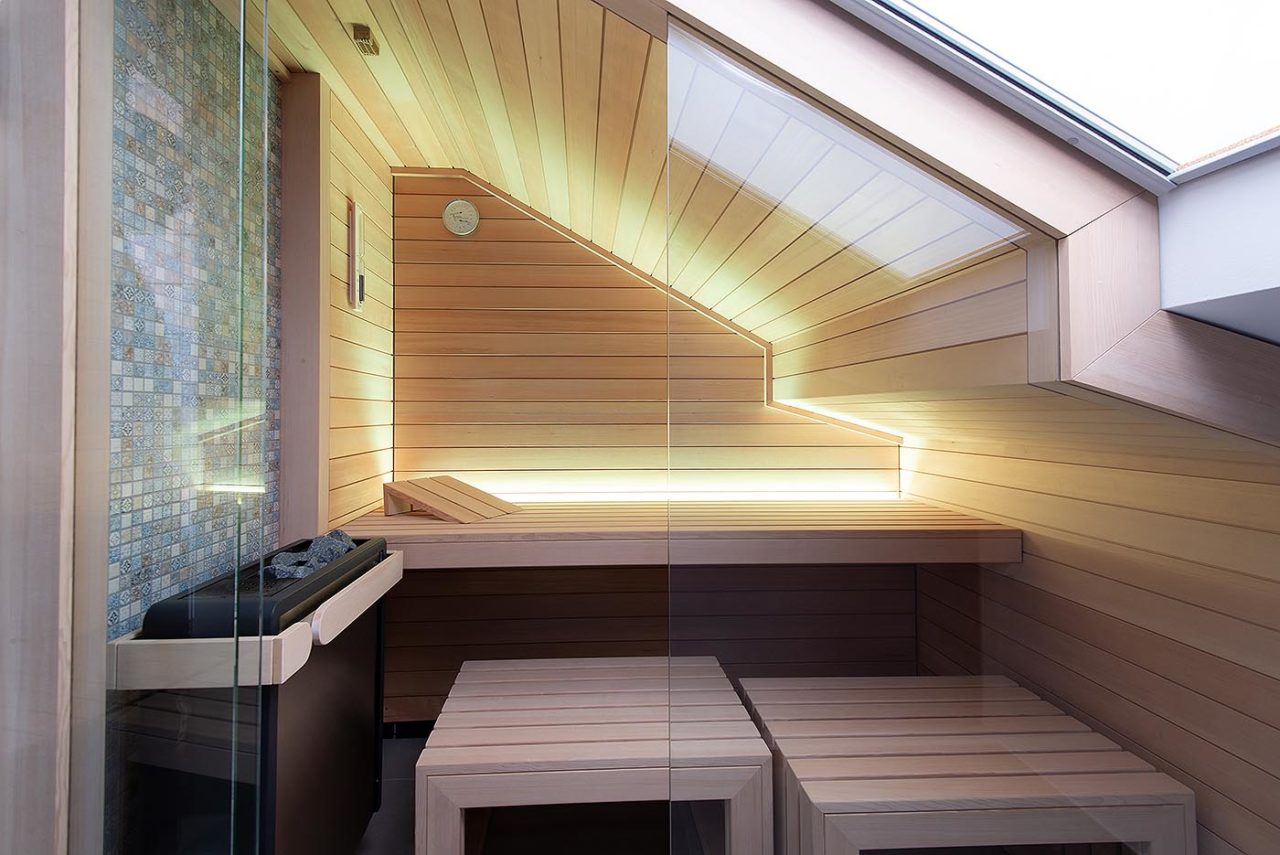 Design Sauna Maßanfertigung unter der Dachschräge mit indirekter LED Beleuchtung in hellem Saunaholz.