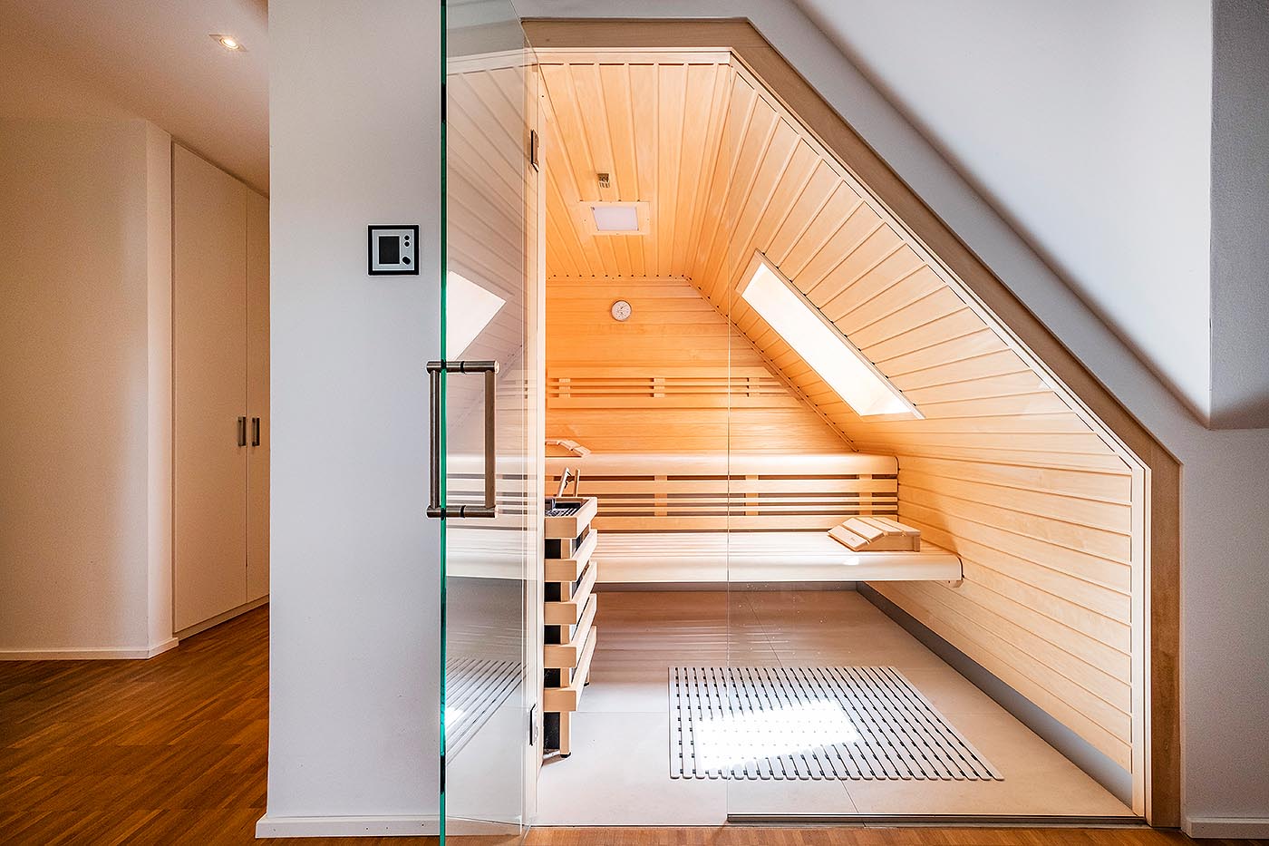 Innensauna planen: Helle Sauna unter der Dachschräge mit integriertem Veluxfenster und Glasfront. Moderne, helle Heimsauna für Zuhause. Individuell geplante und nach Maß gefertigte Dachschrägen-Sauna für Zuhause.