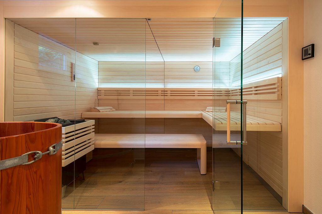 Sauna für Zuhause in hellem Profilholz mit Glasfront und indirekter LED Beleuchtung. Skandinavisch-ursprünglicher Stil, modern interpretiert. 