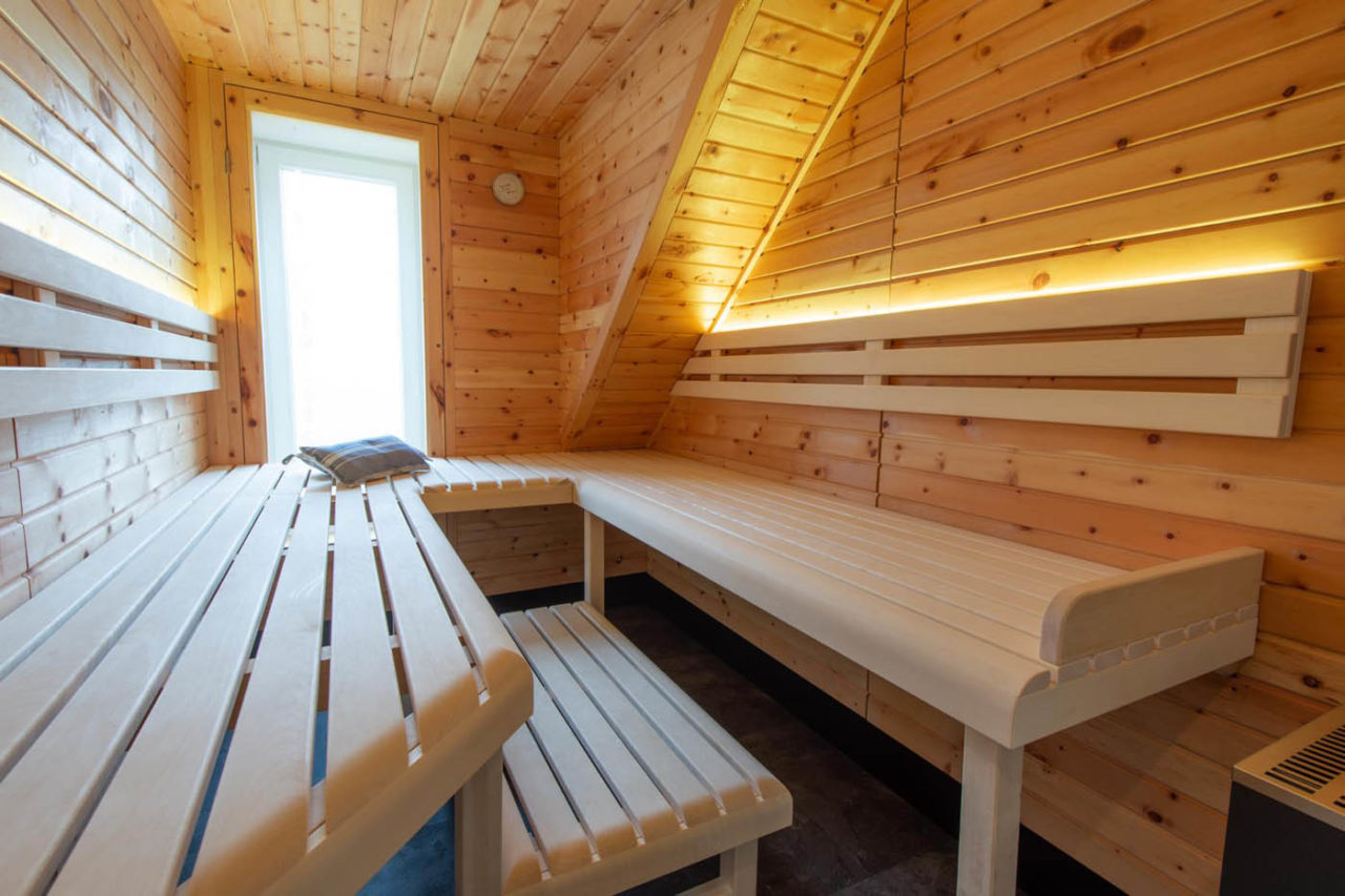 Zirbenholz Sauna unter Dachschräge in Maßanfertigung mit eingearbeitetem Fenster und Glasfront. Sauna mit Dachräge.
