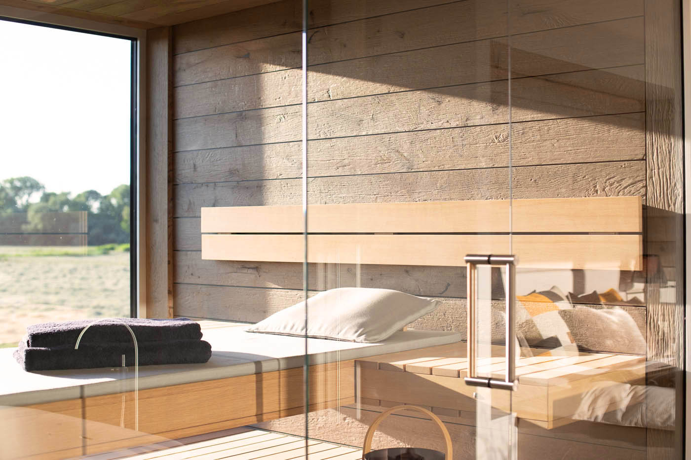 Designsauna nach Maß mit Glasfront und Außenfenster. Schwebende Bänke. Saunabau nach Maß direkt vom Saunahersteller.