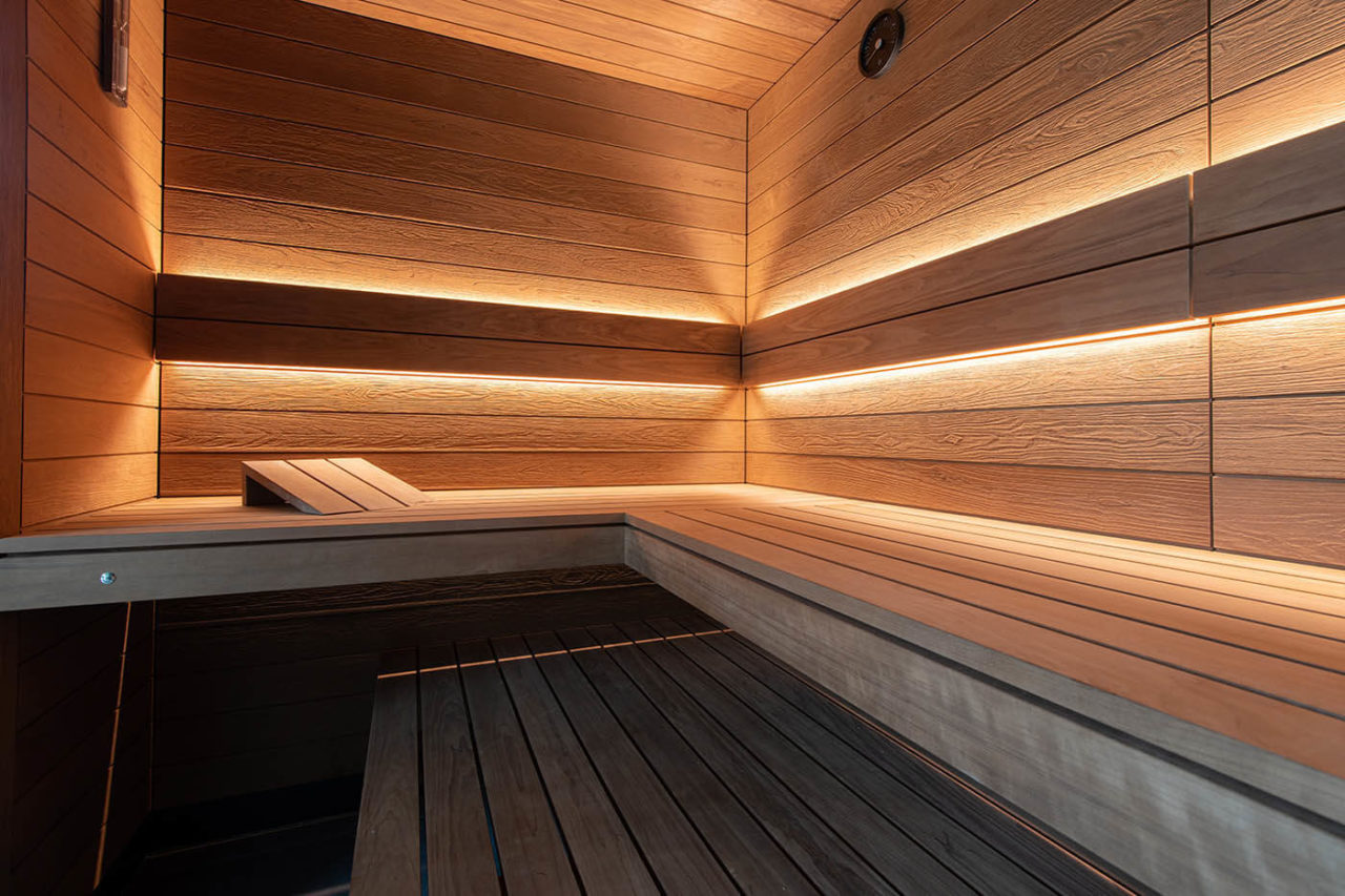 Sauna Zuhause mit Glasfront in Thermo-Espe mit nach außen verlängerter Bank und Blick in den Garten.