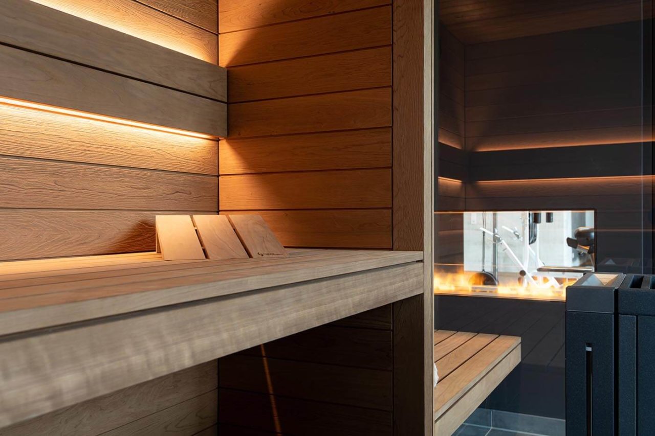 Sauna Zuhause mit Glasfront in gebürsteter Thermo-Espe mit Blick in den Garten und nach außen verlängerter Bank