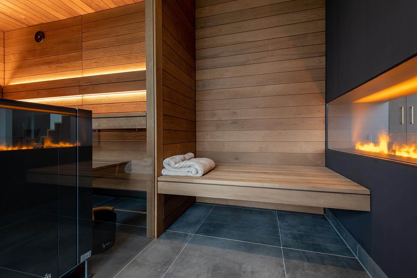 Sauna Zuhause mit Glasfront in Thermo-Espe mit nach außen verlängerter Bank und Blick in den Garten.