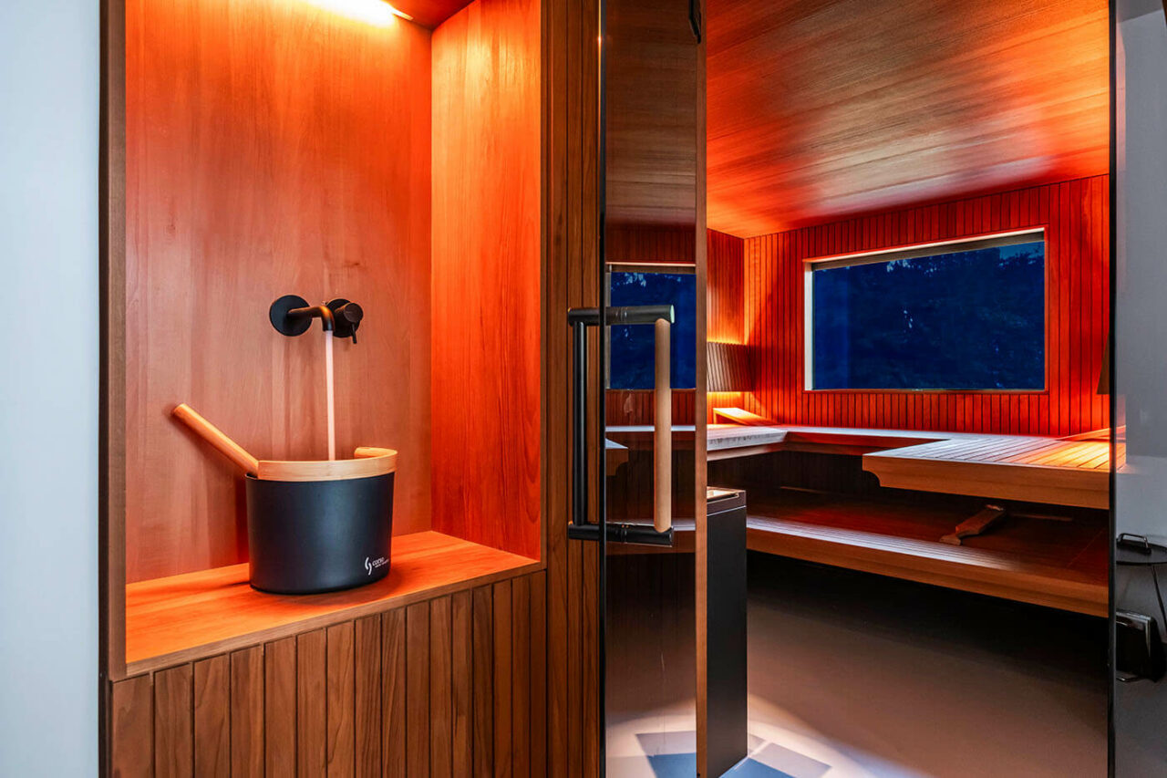 Design Sauna nach Maß mit Glasecke in Thermo-Espe Stäbchenoptik mit indirekter LED Rückenlehnenbeleuchtung und Außenfenster. Biosauna. Saunabau Münster.