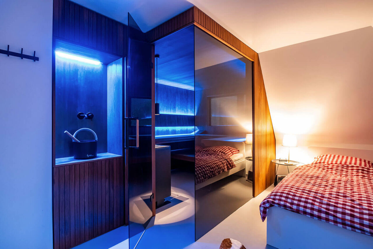 Design Sauna nach Maß mit Glasecke in Thermo-Espe Stäbchenoptik mit indirekter LED Rückenlehnenbeleuchtung und Außenfenster. Biosauna. Saunabau Münster.