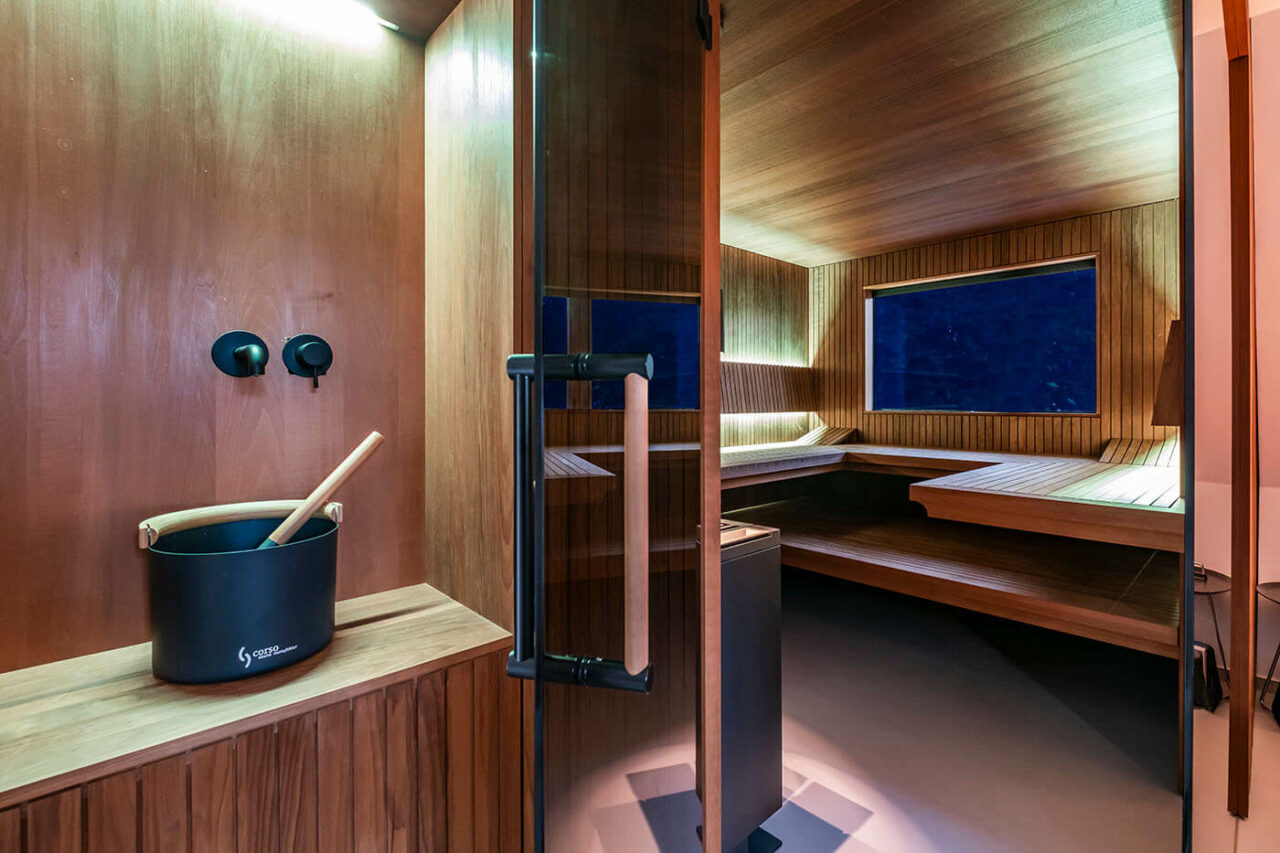 Design Sauna nach Maß mit Glasecke in Thermo-Espe Stäbchenoptik mit indirekter LED Rückenlehnenbeleuchtung und Außenfenster. Biosauna. Saunabau Münster.