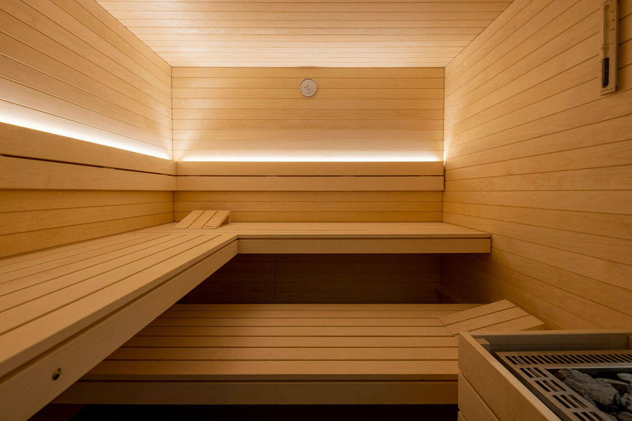 Helle Design Sauna mit indirekter LED Beleuchtung und großzügiger Glasecke. Voll integrierte Einbausauna nach Maß.