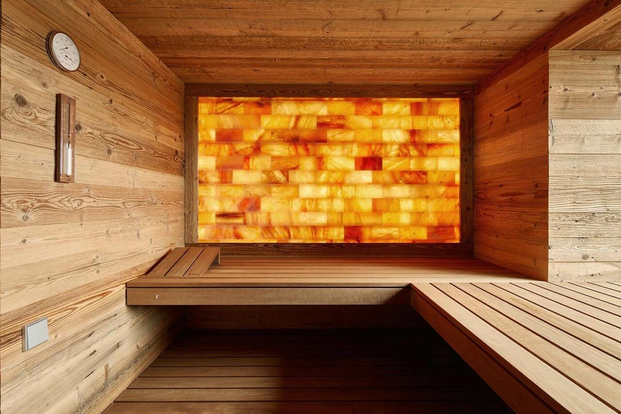 Altholz Sauna mit hellem Altholz und hinterleuchteter Salzsteinwand sowie integriertem Fenster