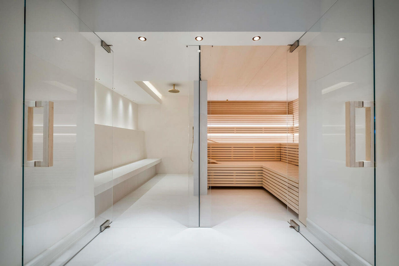 Design Sauna im Bauhausstil mit Hinterwandofen. Saunaholz: helle Espe in Stäbchenoptik. Große Glasfront, LED Beleuchtung, Hinterwandofen.