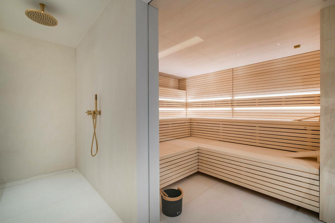 Design Sauna im Bauhausstil mit Hinterwandofen. Saunaholz: helle Espe in Stäbchenoptik. Große Glasfront, LED Beleuchtung, Hinterwandofen.