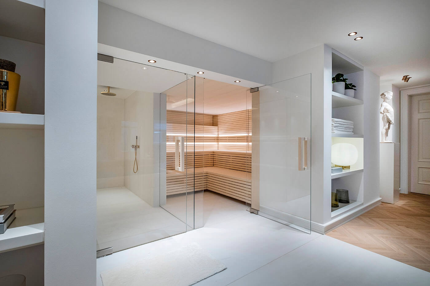 Design Sauna im Bauhausstil mit Hinterwandofen. Saunaholz: helle Espe in Stäbchenoptik. Große Glasfront, LED Beleuchtung, Hinterwandofen.