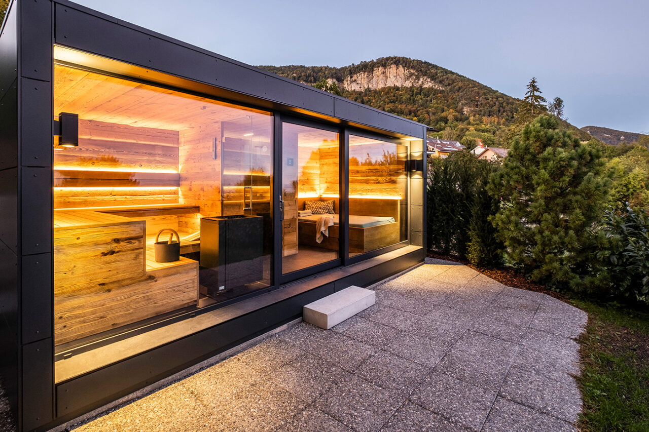 Hochwertige moderne Außensauna mit Glasfront, Ruheraum, Dusche und Sauna aus Altholz. Maßanfertigung der corso sauna manufaktur. Lieferung per Autokran.