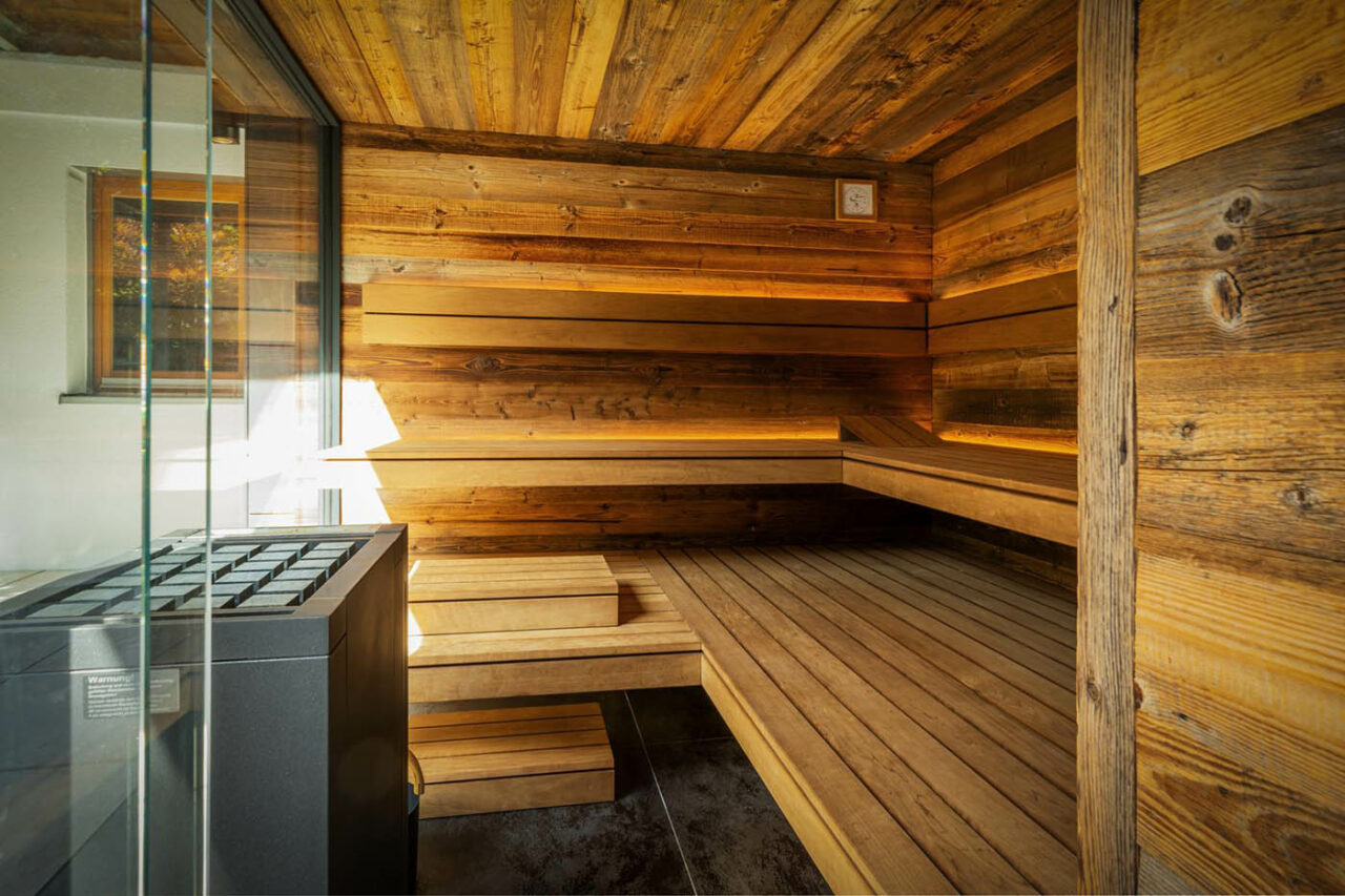 Luxus Außensauna: individuell geplante und gebaute Gartensauna in Altholz mit Sauna, Ruheraum mit Wasserbett und Regendusche von Dornbracht sowie Verdunkelung von Warema