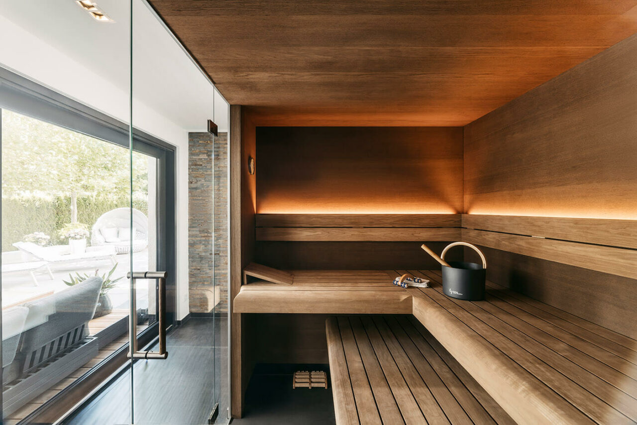 Design Sauna mit Glasfront in Thermo-Eiche mit frei stehendem Saunaofen und LED Beleuchtung. Massanfertigung.