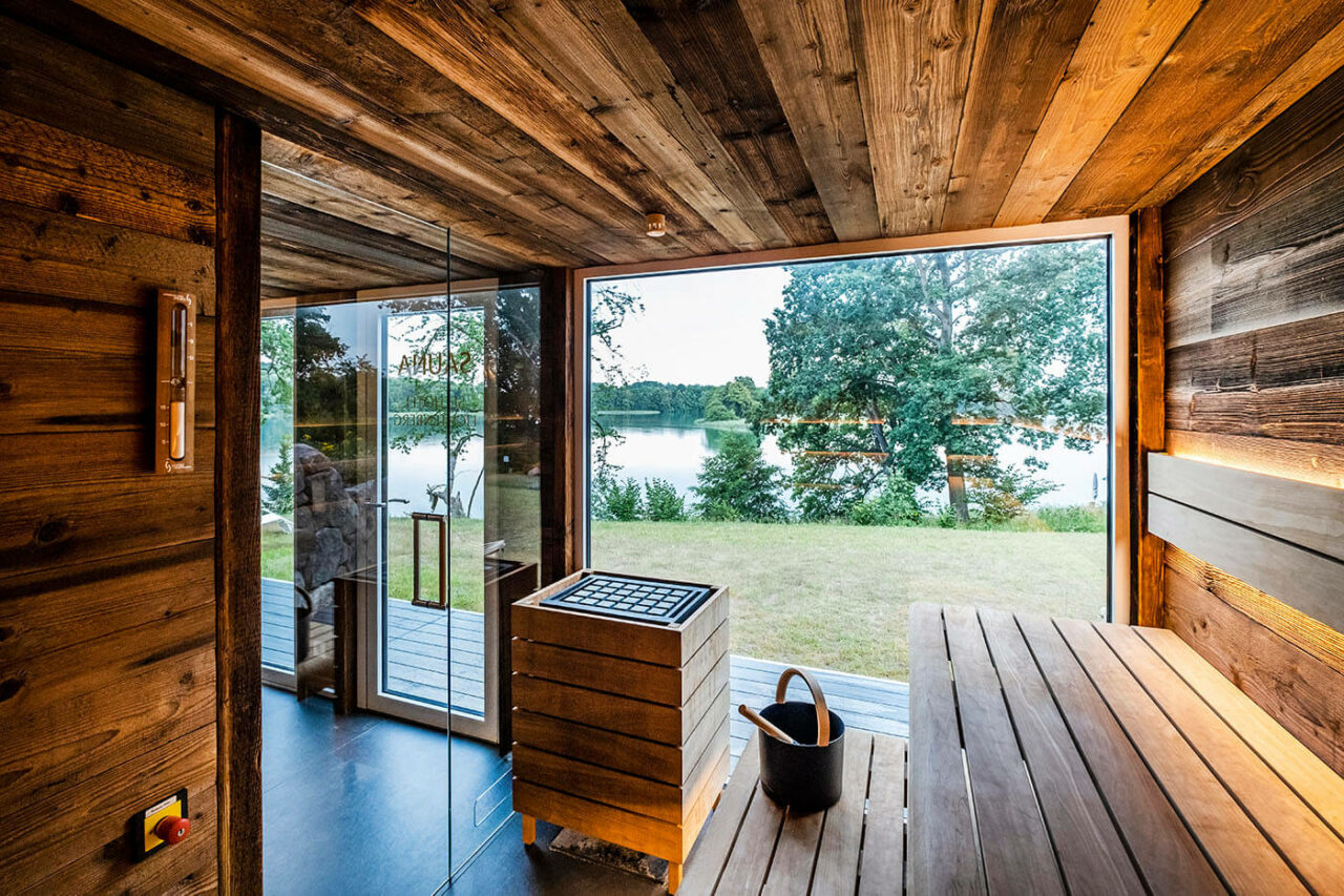 Saunahaus als Hotel SPA: Gartensauna im Außenbereich direkt am See beim Hotel Lichtenberg mit Ruheraum und Dusche. Innengestaltung in Altholz, Außengestaltung passend zum Hotel.