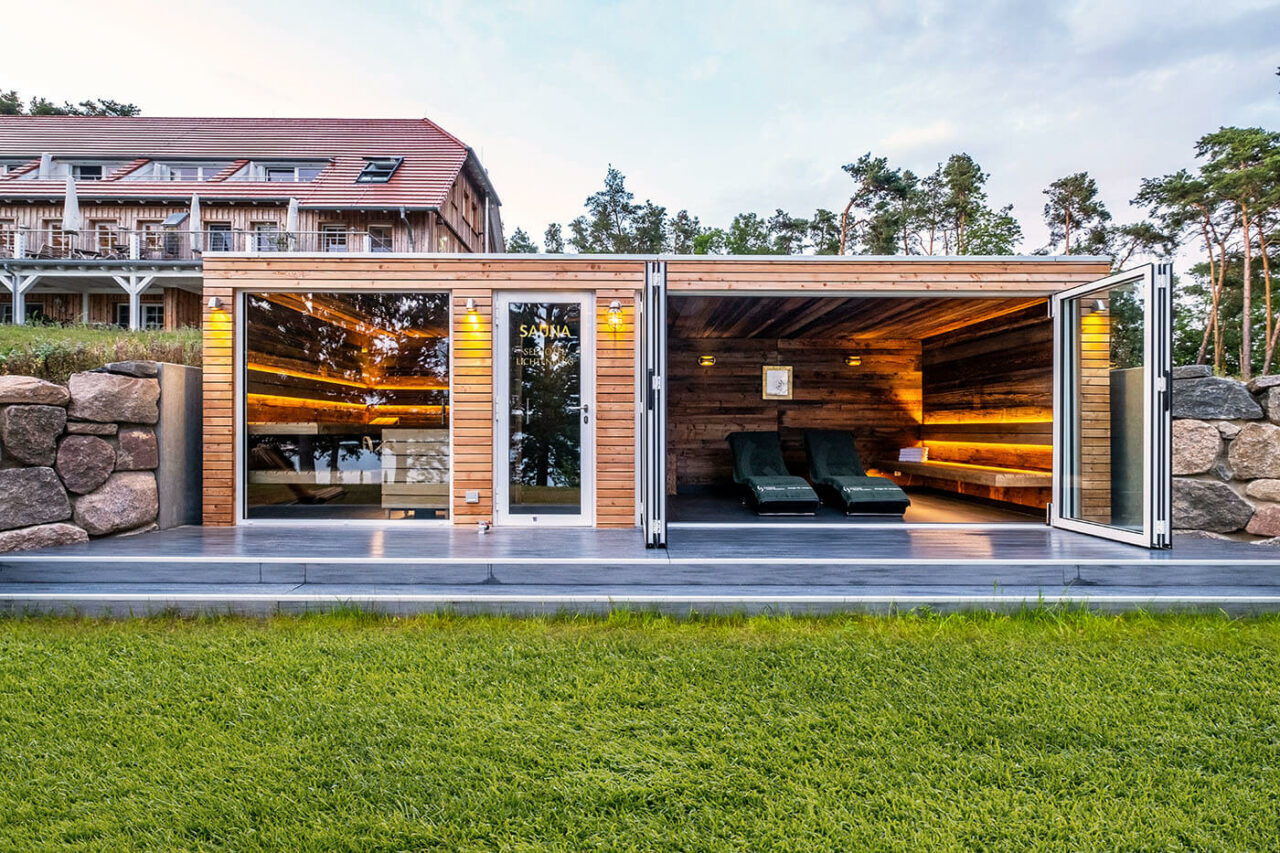 Außensauna Hotel: Gartensauna im Außenbereich direkt am See beim Hotel Lichtenberg mit Ruheraum und Dusche. Innengestaltung in Altholz, Außengestaltung passend zum Hotel.