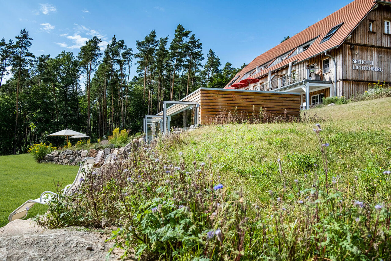 Außensauna Hotel: Gartensauna im Außenbereich direkt am See beim Hotel Lichtenberg mit Ruheraum und Dusche. Innengestaltung in Altholz, Außengestaltung passend zum Hotel.