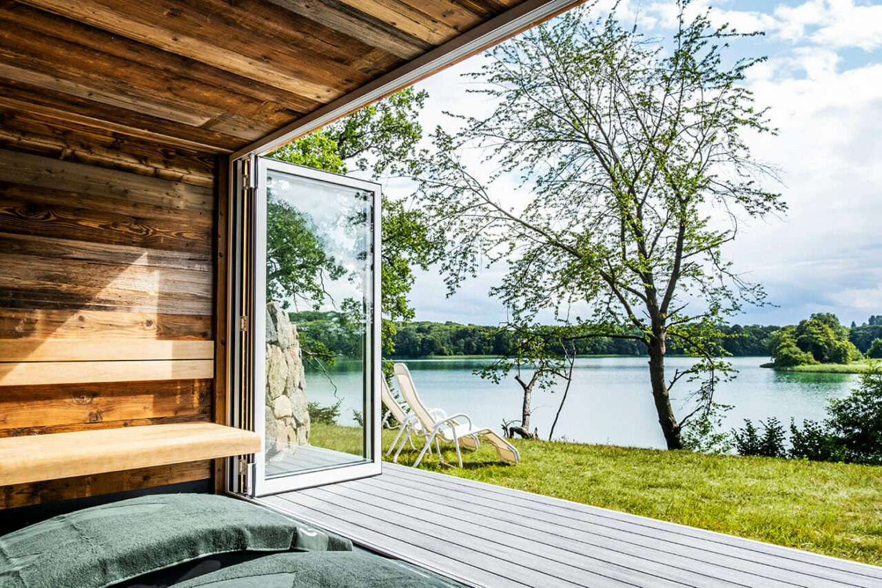 Außensauna Hotel: Gartensauna im Außenbereich direkt am See beim Hotel Lichtenberg mit Ruheraum und Dusche. Innengestaltung in Altholz, Außengestaltung passend zum Hotel.