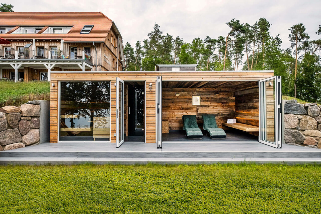 Außensauna Hotel: Gartensauna im Außenbereich direkt am See beim Hotel Lichtenberg mit Ruheraum und Dusche. Innengestaltung in Altholz, Außengestaltung passend zum Hotel.