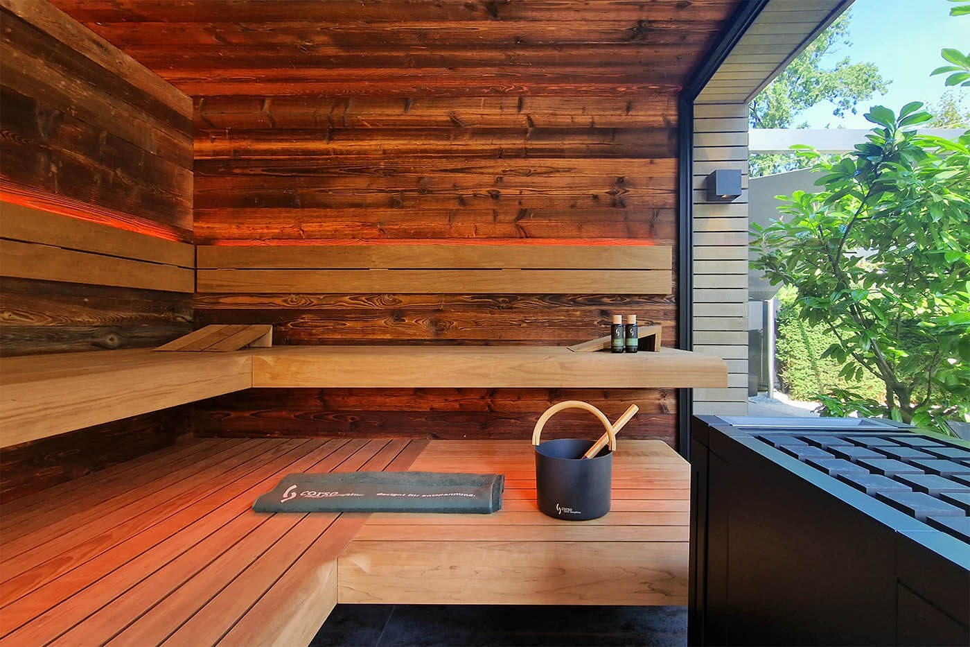 Gartensauna mit Dusche und Ruheraum. Blick aus der Altholz-Sauna auf den Außenbereich.