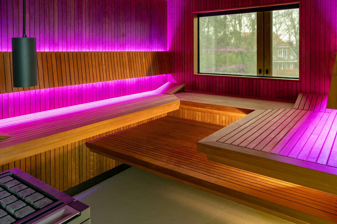 Design Sauna nach Maß mit Glasecke in Thermo-Espe Stäbchenoptik mit indirekter LED Rückenlehnenbeleuchtung und Außenfenster. Biosauna. Saunabau Münster.