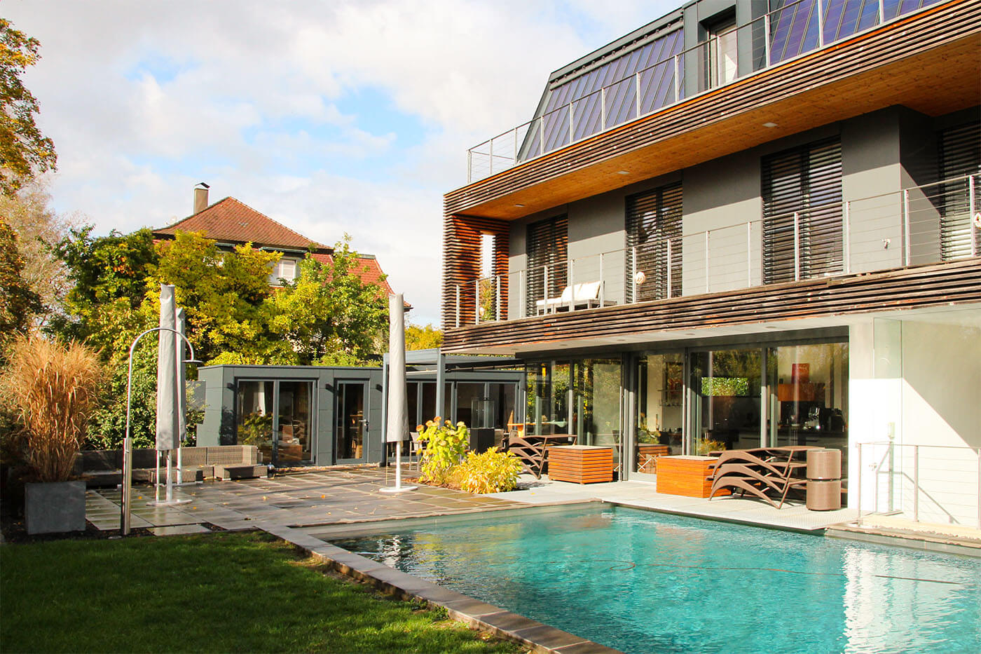 Custom-made pool house with opening glass front, daybed, coffee kitchen and lounge. Exterior cladding in weatherproof Trespa laminate panels.