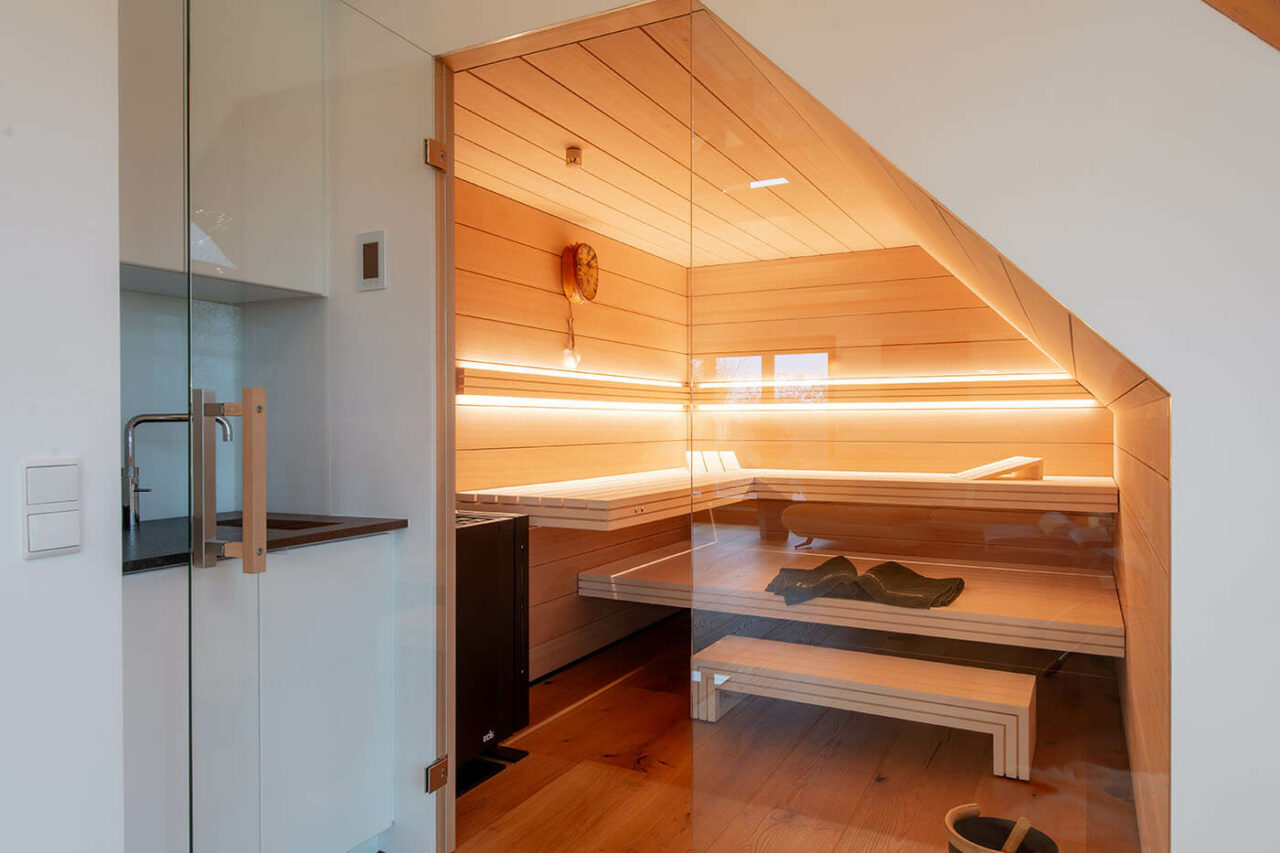 Sauna nach Maß: Hemlock Sauna mit Dachschräge und großer Glasfront.