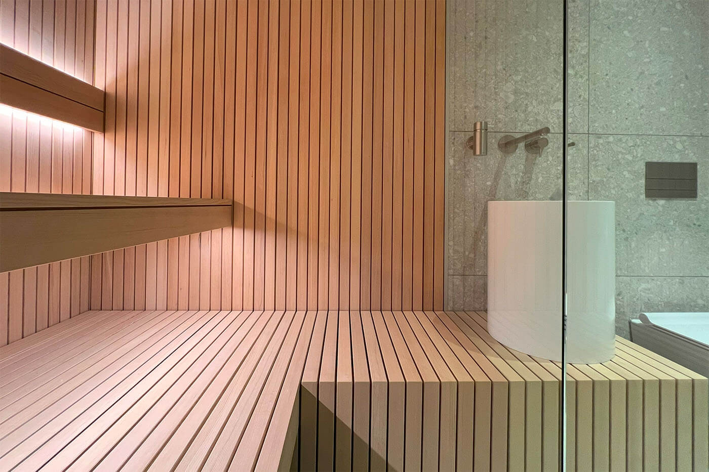 Hemlock Sauna in Stäbchenoptik als Maßanfertigung mit großer Glasfront und nach außen verlängerter Bank. Direkt vom Saunabauer.