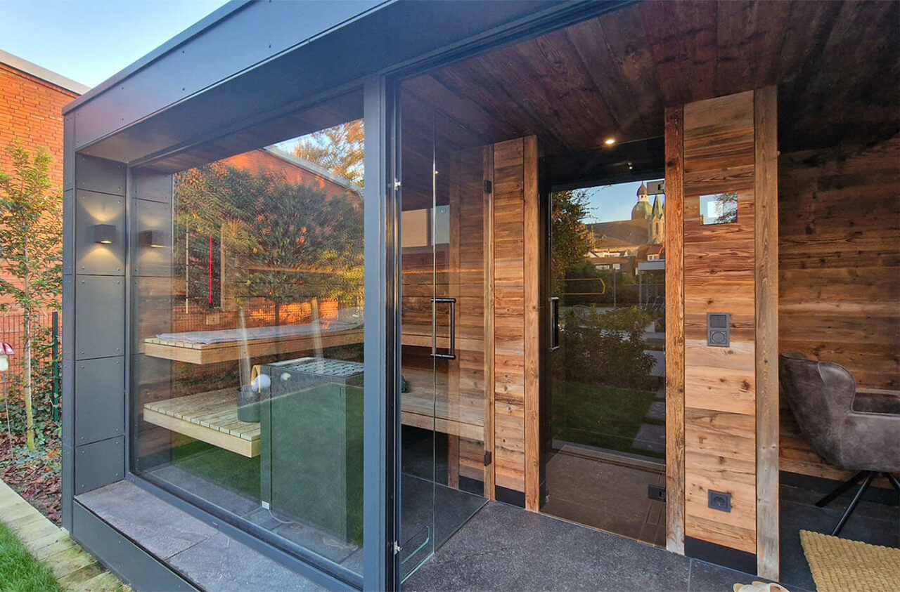 Gartensauna mit Daybed und Dusche in Altholz. Glasfront mit Schiebetür.