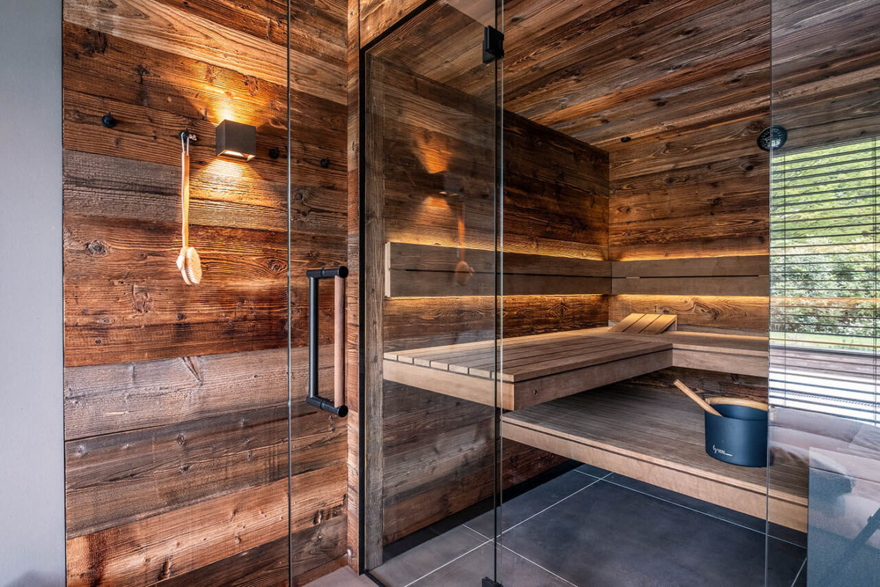 Altholzsauna mit Glasfront und nach außen fortgeführter Wand. Maßanfertigung direkt neben der Dusche.