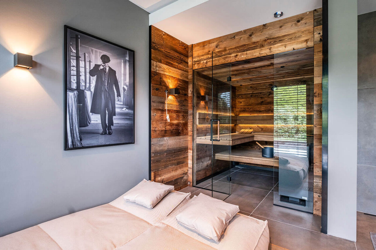 Altholzsauna mit Glasfront und nach außen fortgeführter Wand. Maßanfertigung direkt neben der Dusche.