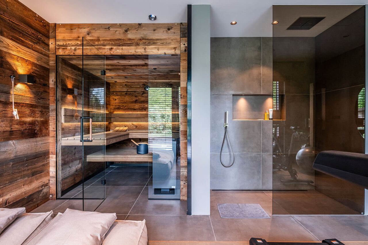 Altholzsauna mit Glasfront und nach außen fortgeführter Wand. Maßanfertigung direkt neben der Dusche.