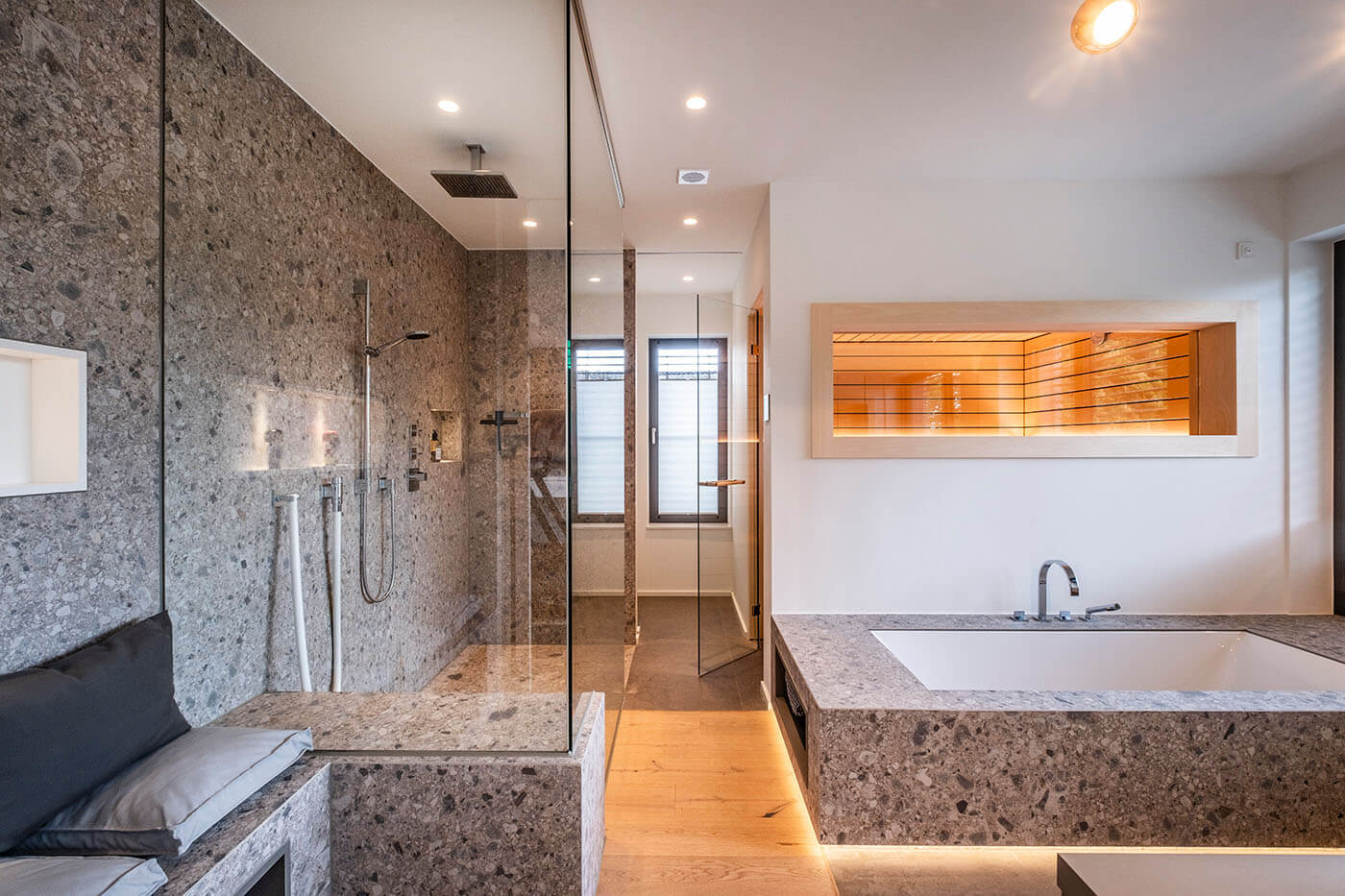 Sauna im Bad in heller Espe mit Glastür und Indoor-Fenster Richtung Bad. Designsauna nach Maß mit Doppelnutprofil und indirekter LED Beleuchtung.