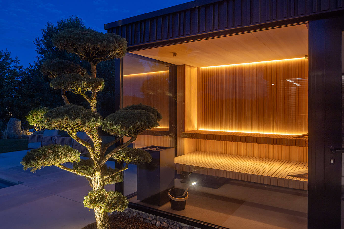 Gartensauna am Pool in Hemlockholz Stäbchenoptik mit gerader Vorderkante. Indirekte Beleuchtung mit LED.